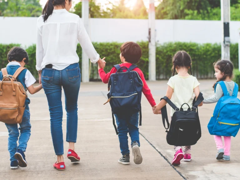 students holding hands with teacher walking to class