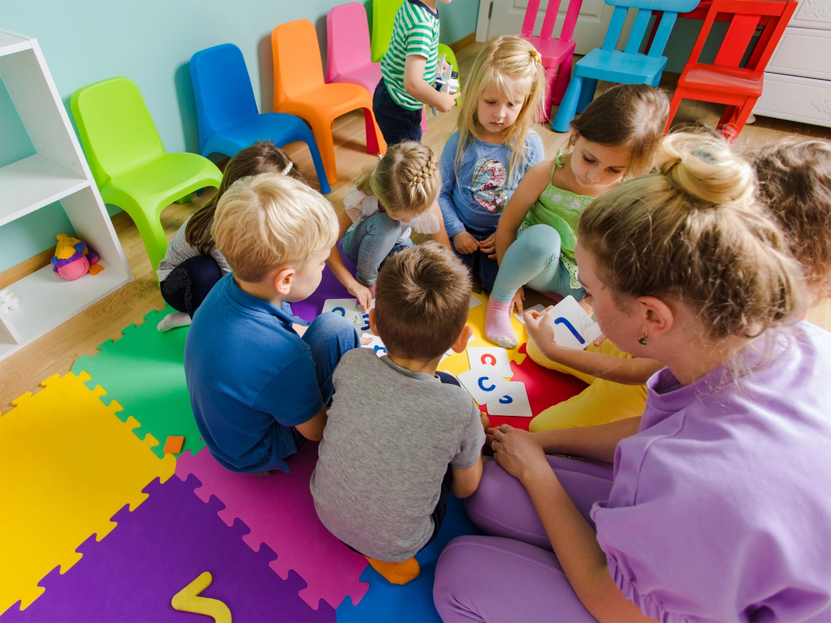 daycare students and teacher sitting down playing a card activity